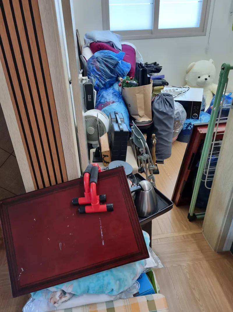 이불과 소형 가전, 잡동사니가 가득 쌓인 수거 전 작은 방